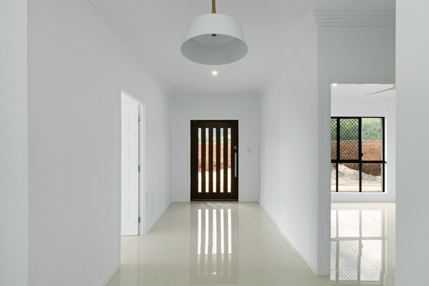 An Empty Hallway With a Door and a Light Hanging From the Ceiling — Ashlee Jones Homes in Gordonvale, QLD