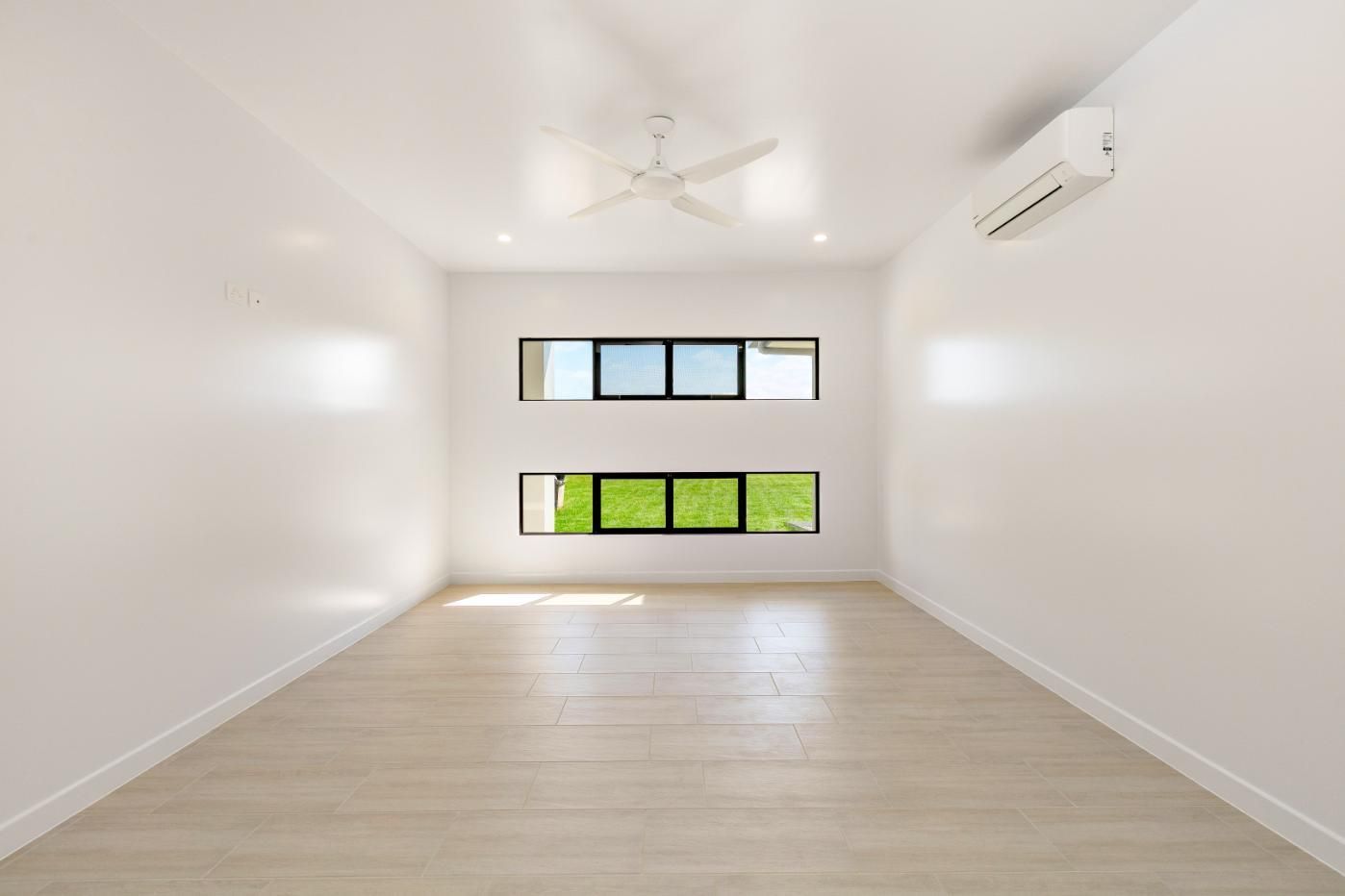 An Empty Room With Two Windows and a Ceiling Fan — Ashlee Jones Homes in Gordonvale, QLD