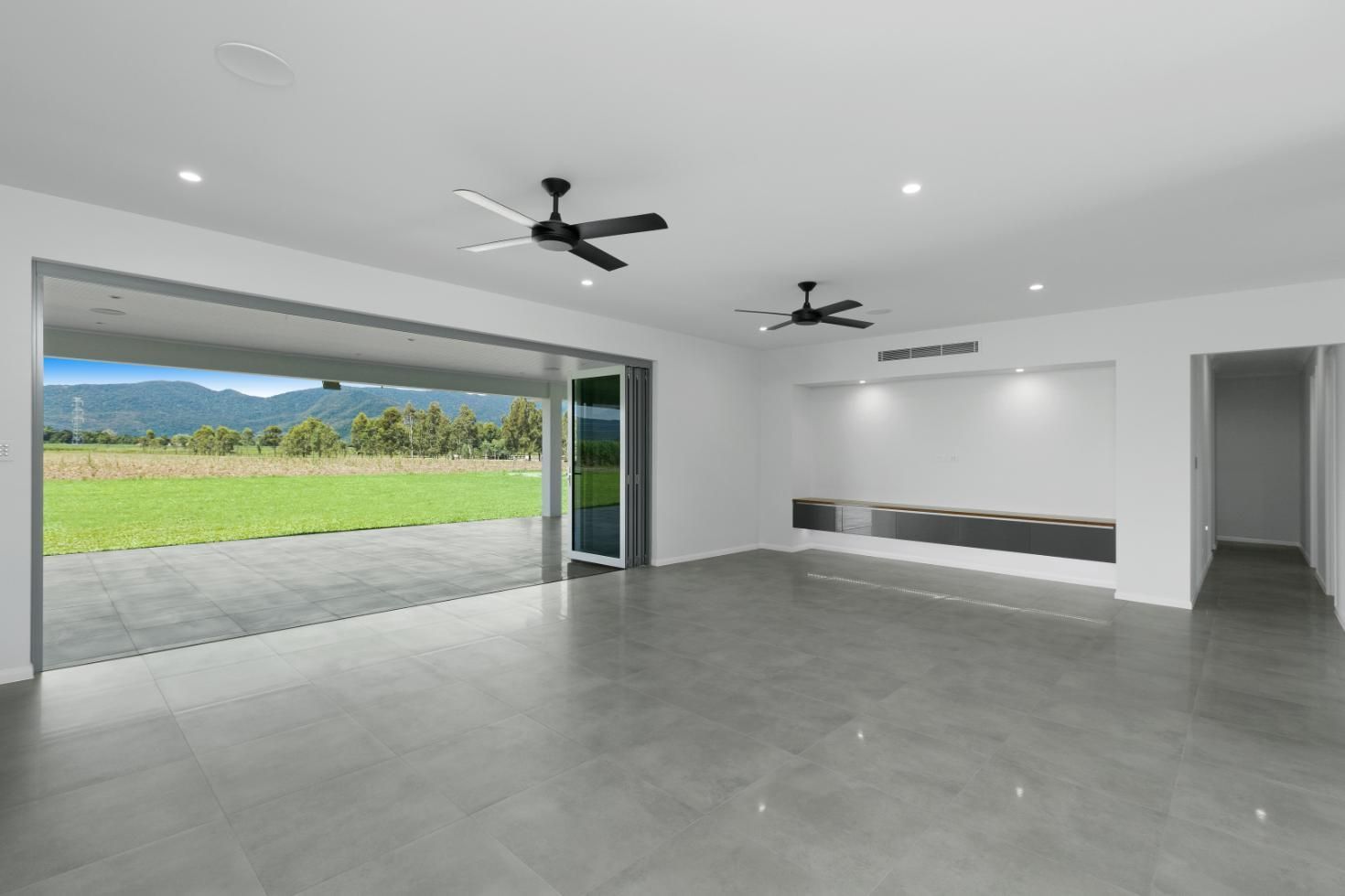 A Large Empty Room With Two Ceiling Fans and a Sliding Glass Door — Ashlee Jones Homes in Gordonvale, QLD