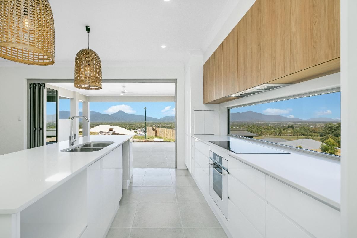 A Kitchen With White Cabinets and Wooden Cabinets and a Large Window — Ashlee Jones Homes in Gordonvale, QLD