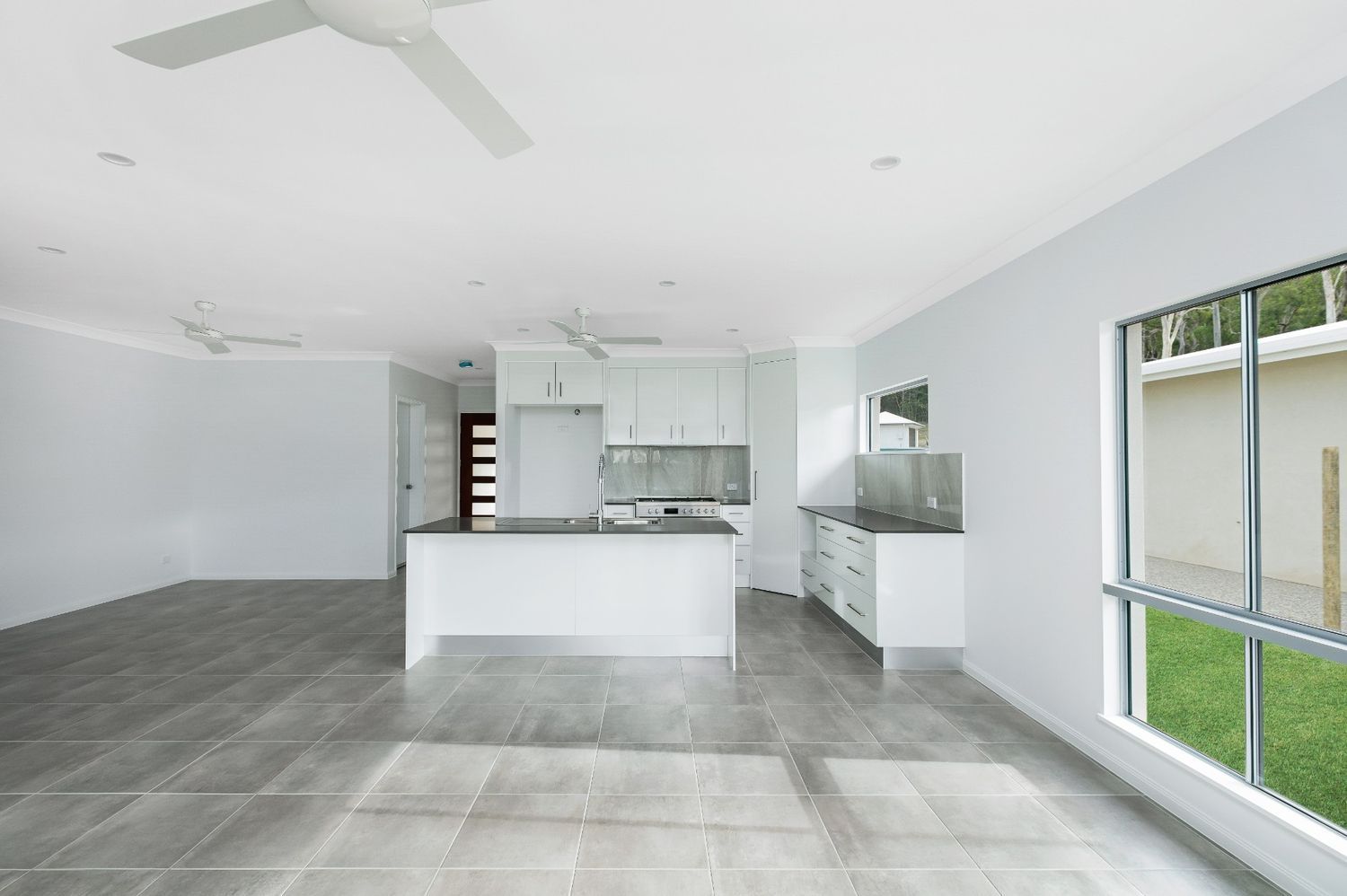 An Empty Room With a Kitchen and a Ceiling Fan — Ashlee Jones Homes in Gordonvale, QLD