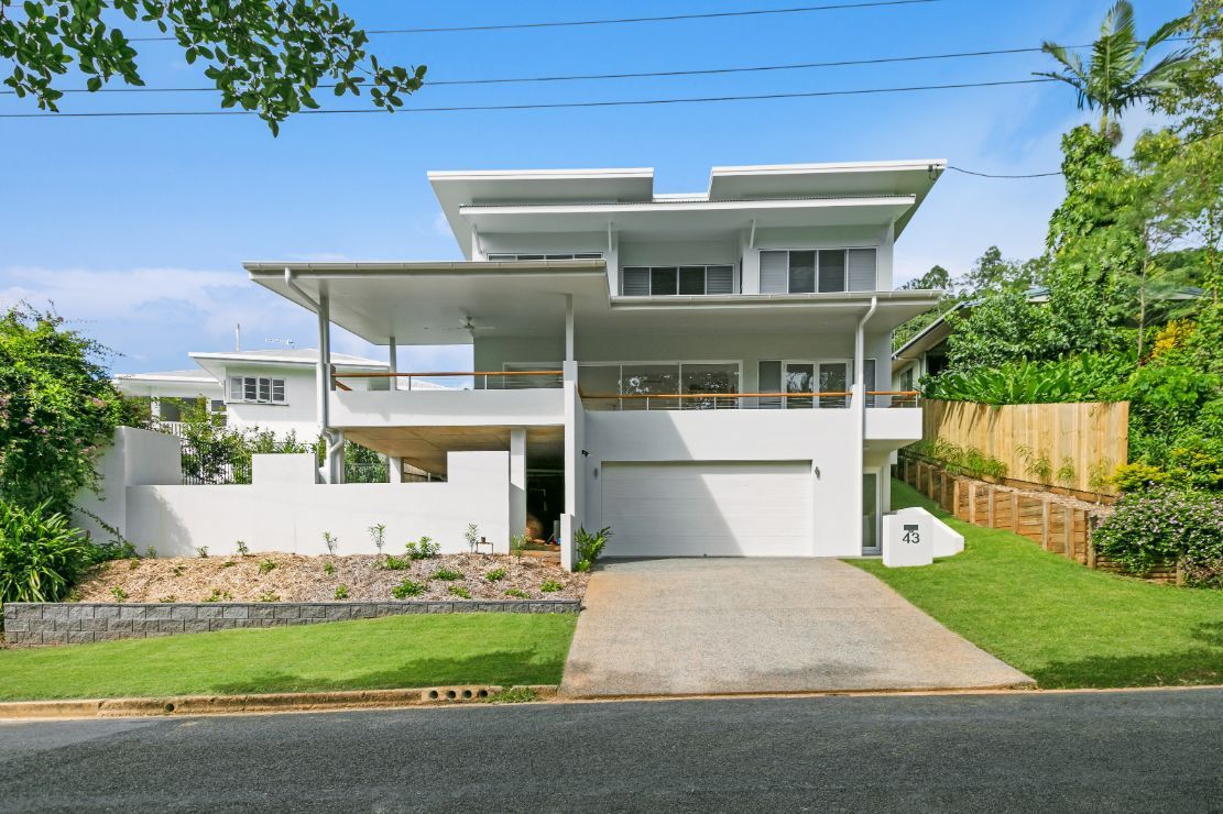 A Large White House is Sitting on Top of a Lush Green Hillside — Ashlee Jones Homes in Gordonvale, QLD