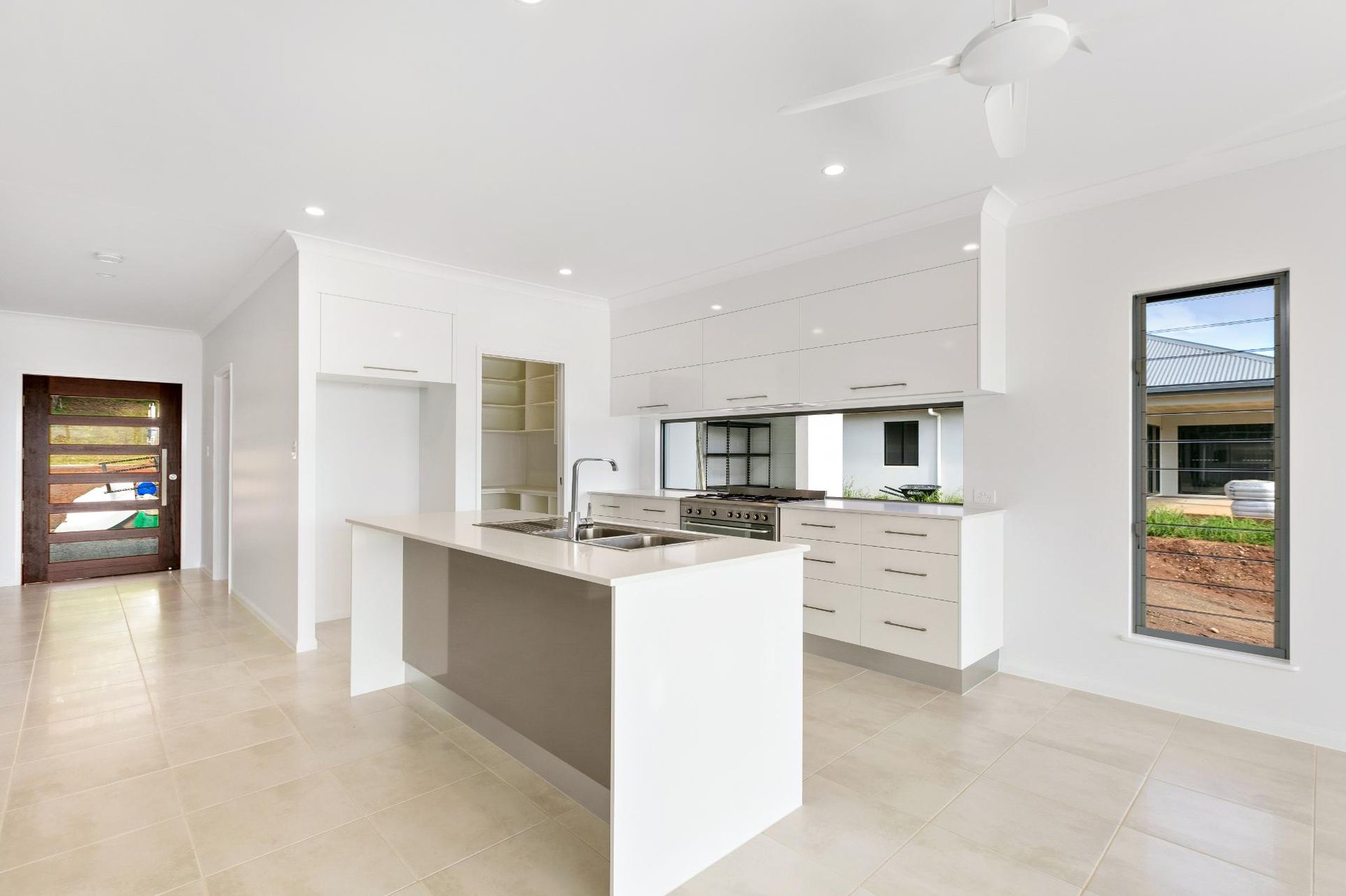 An Empty Kitchen With a Large Island in the Middle of the Room — Ashlee Jones Homes in Gordonvale, QLD