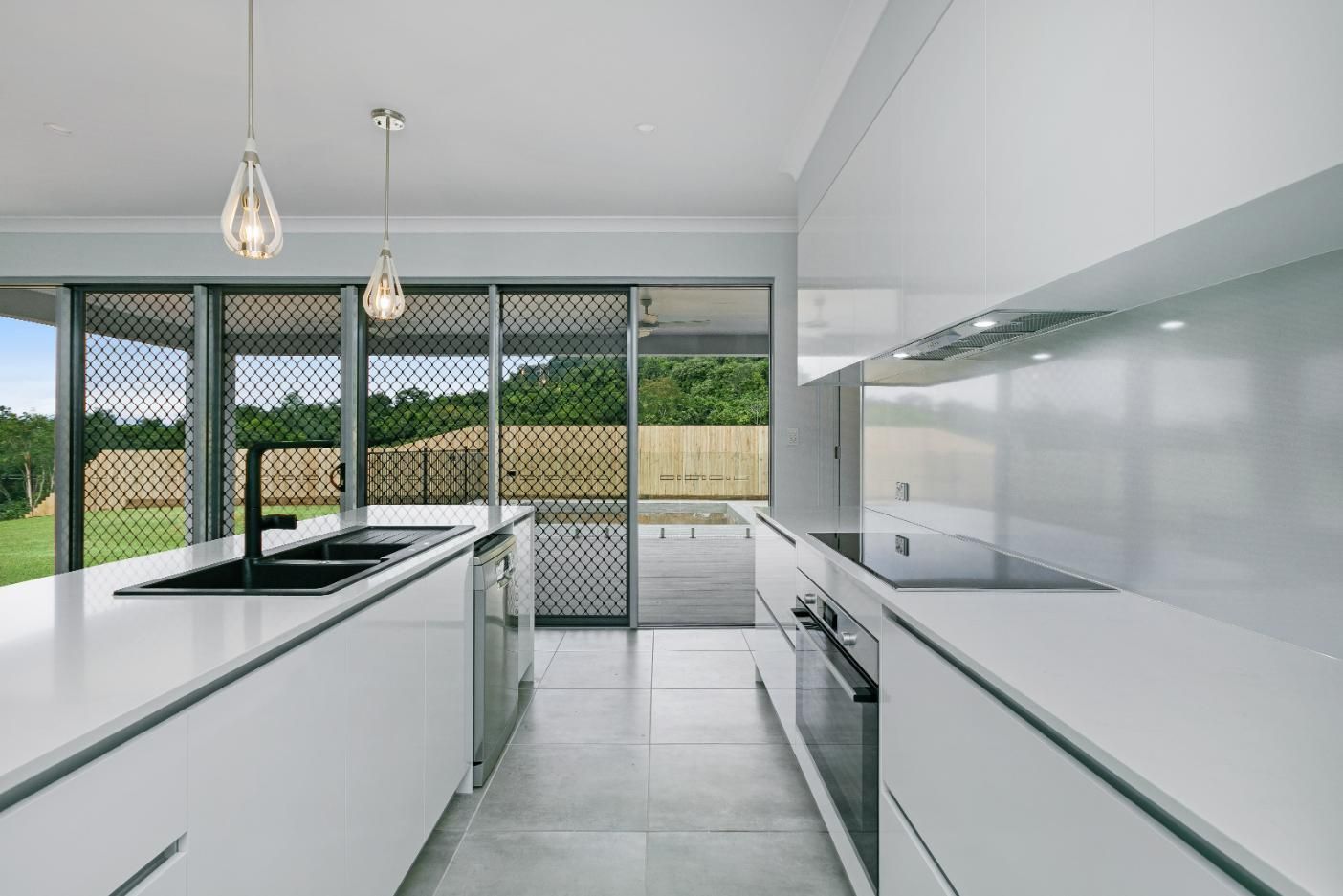 A Kitchen With White Cabinets, Stainless Steel Appliances, and a Large Island — Ashlee Jones Homes in Gordonvale, QLD