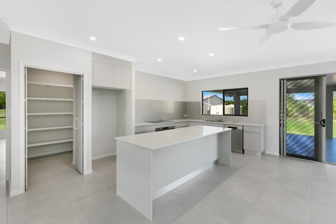 A Kitchen With a Large Island and a Ceiling Fan — Ashlee Jones Homes in Gordonvale, QLD