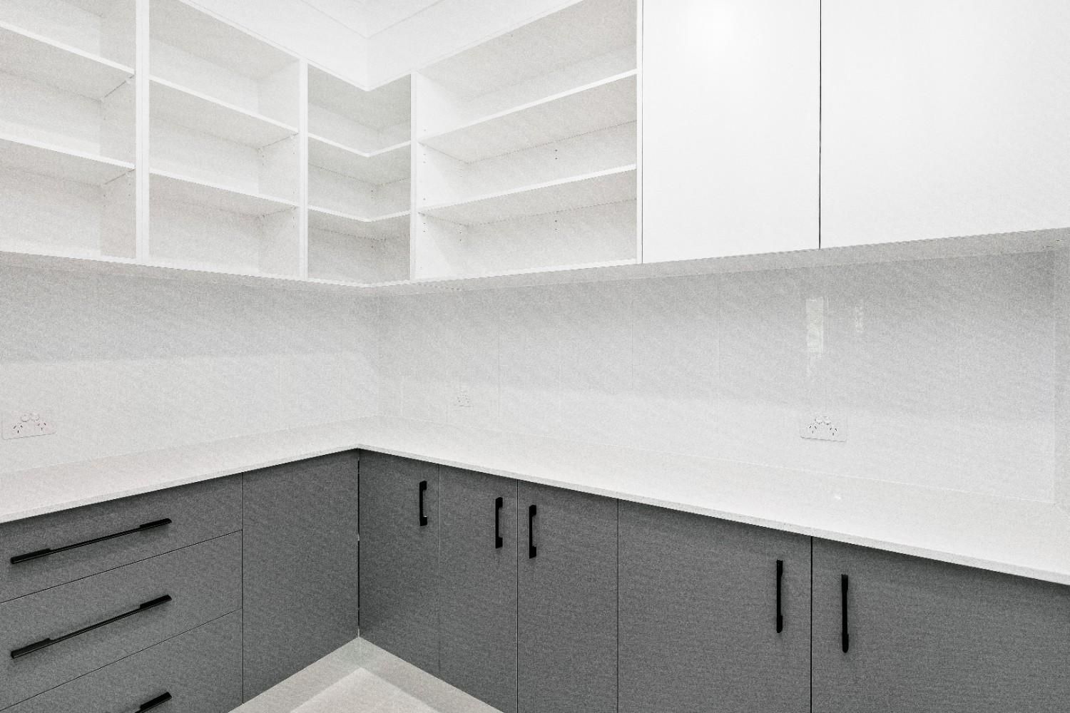 A Kitchen With Gray Cabinets and White Counter Tops — Ashlee Jones Homes in Gordonvale, QLD