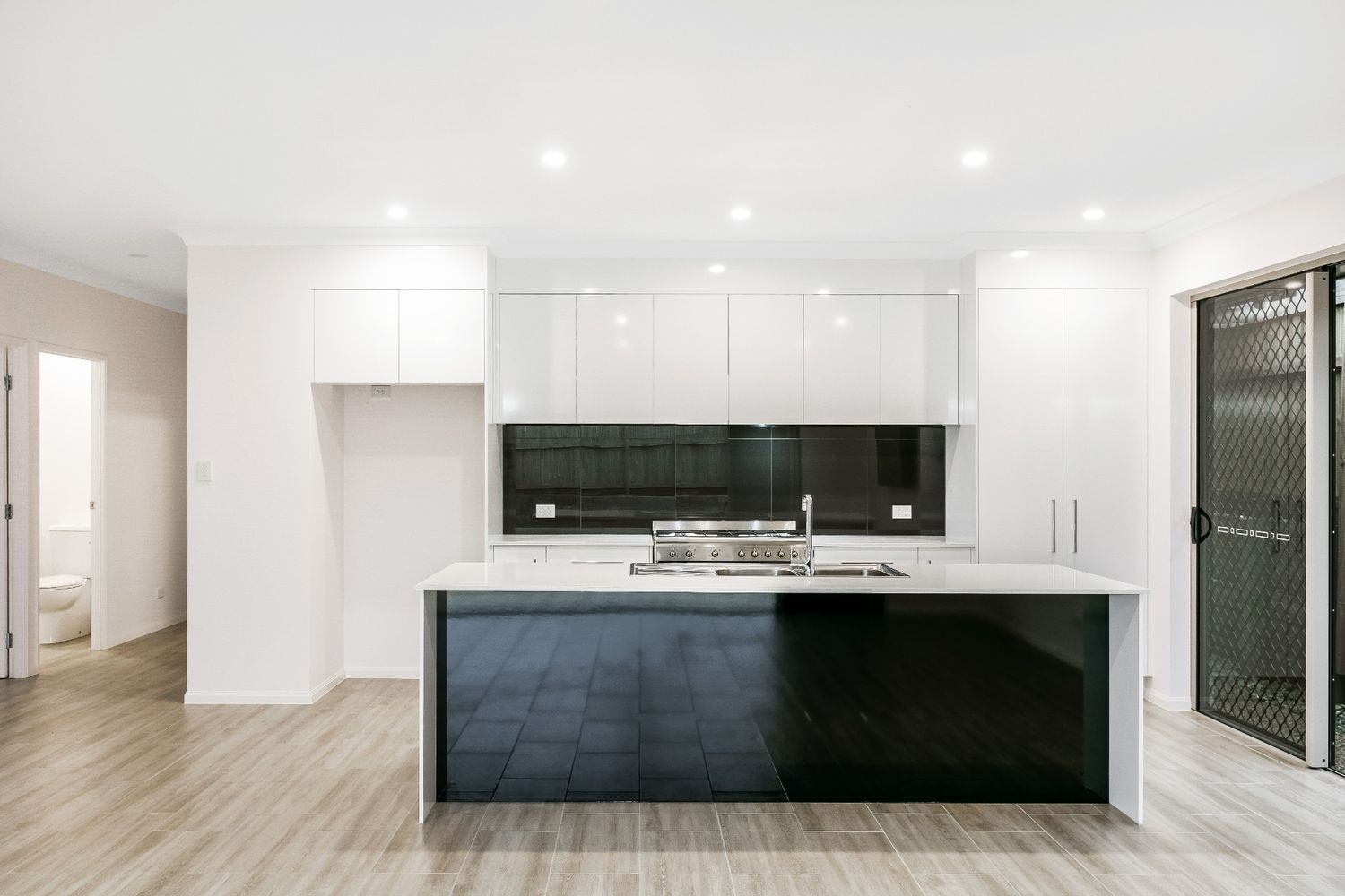 A Kitchen With White Cabinets and a Black Island — Ashlee Jones Homes in Gordonvale, QLD