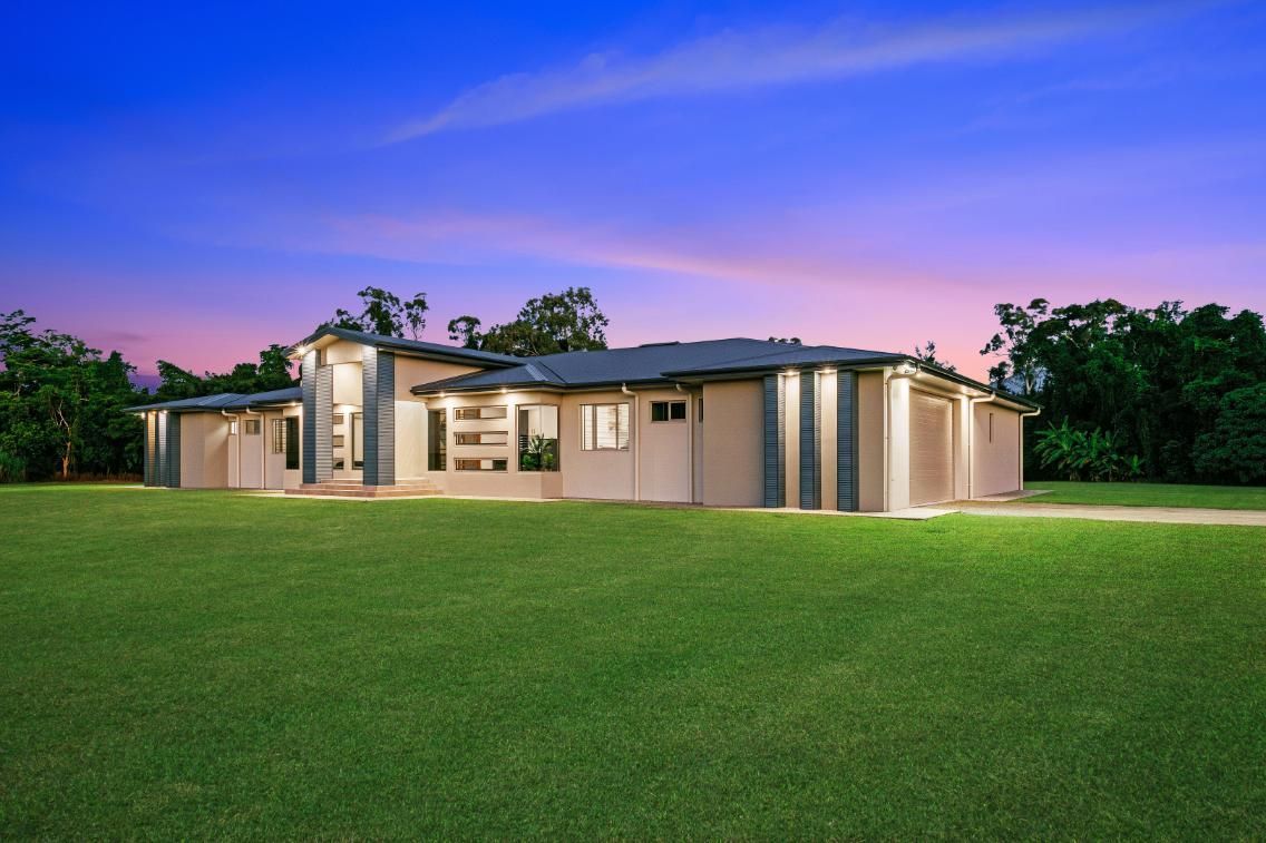 A Large House is Sitting on Top of a Lush Green Field — Ashlee Jones Homes in Gordonvale, QLD