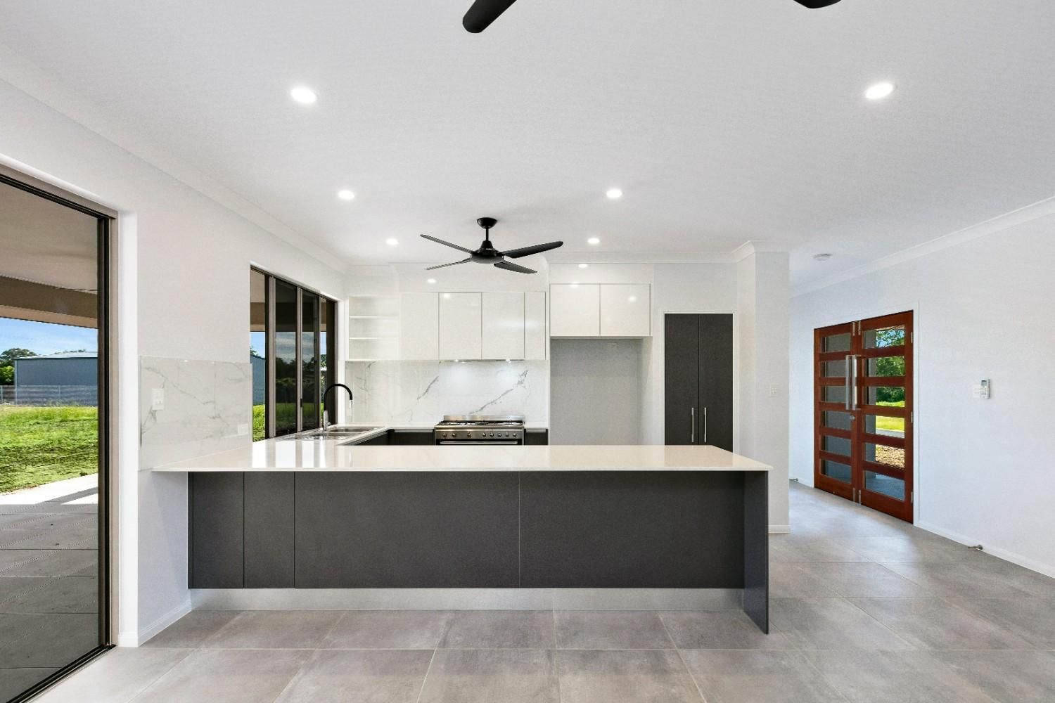 A Kitchen With a Large Island and a Ceiling Fan — Ashlee Jones Homes in Gordonvale, QLD