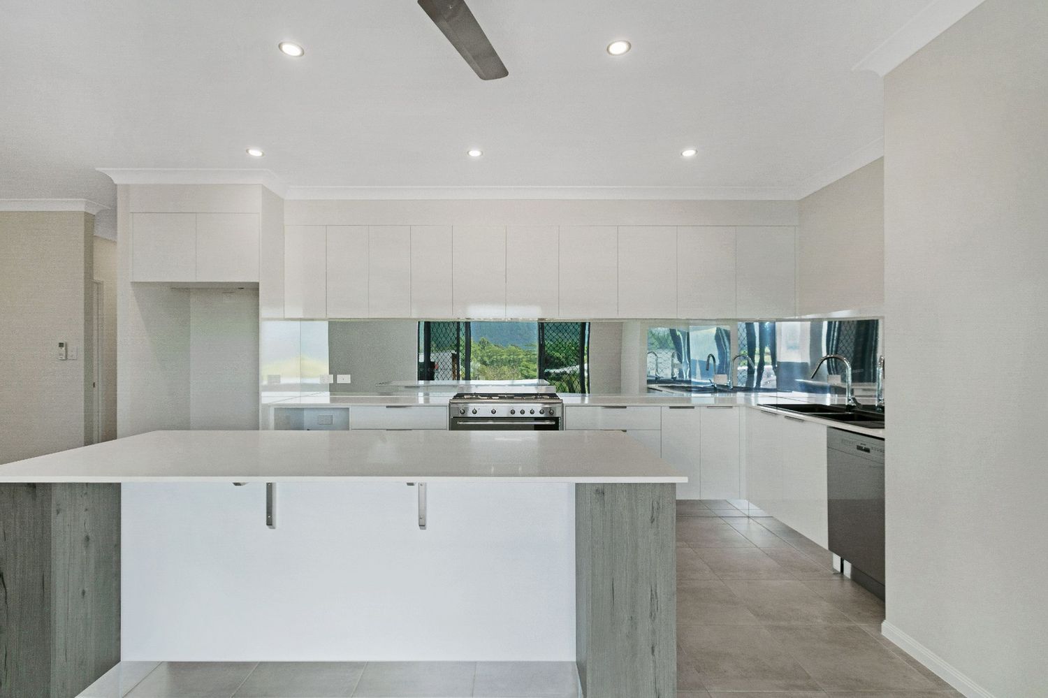 An Empty Kitchen With a Large Island and a Ceiling Fan — Ashlee Jones Homes in Gordonvale, QLD