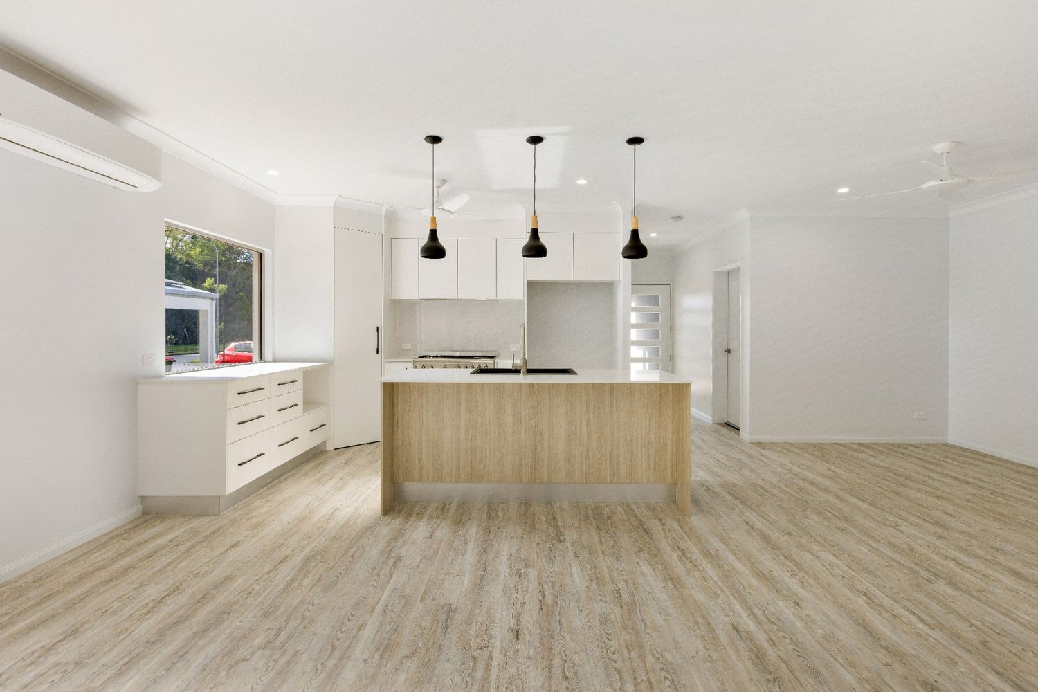 An Empty Kitchen With a Wooden Island and White Cabinets — Ashlee Jones Homes in Gordonvale, QLD