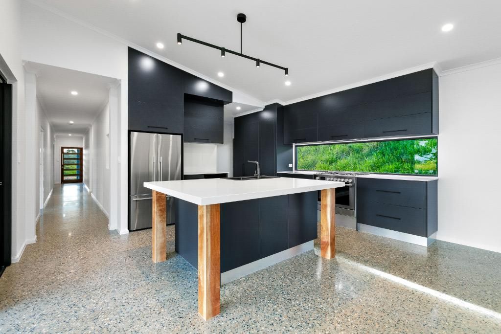 A Kitchen With Black Cabinets and a Large Island in the Middle of the Room — Ashlee Jones Homes in Gordonvale, QLD