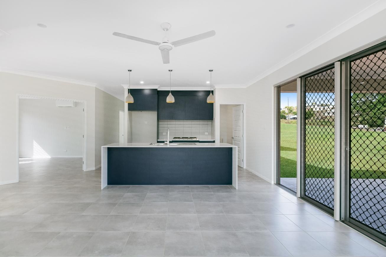 An Empty Kitchen With a Ceiling Fan and Sliding Glass Doors — Ashlee Jones Homes in Gordonvale, QLD
