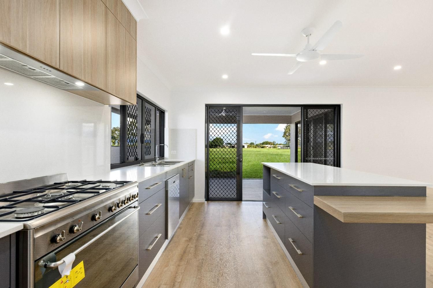 A Kitchen With Stainless Steel Appliances and a Large Island — Ashlee Jones Homes in Gordonvale, QLD