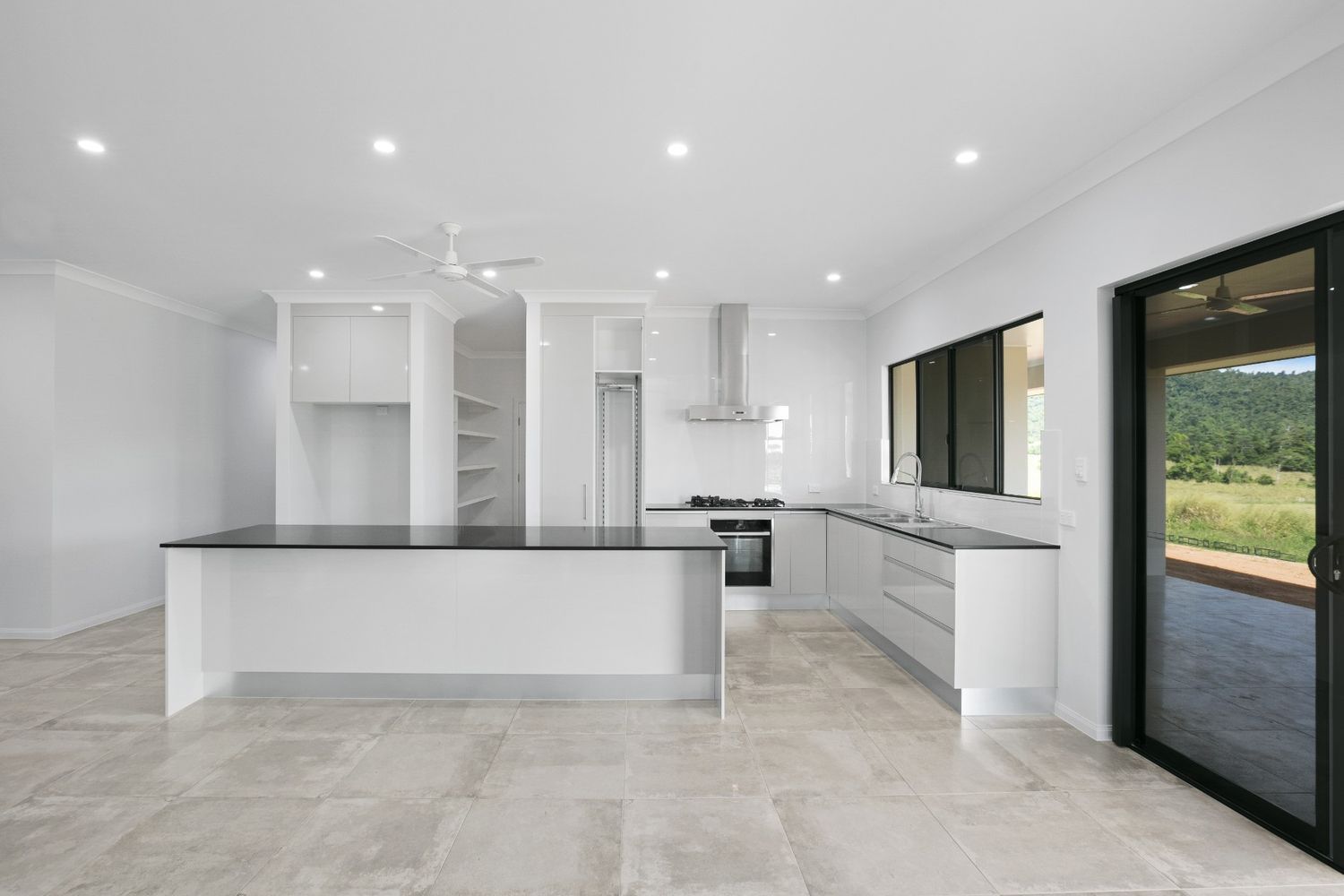 An Empty Kitchen With White Cabinets and Black Counter Tops — Ashlee Jones Homes in Gordonvale, QLD