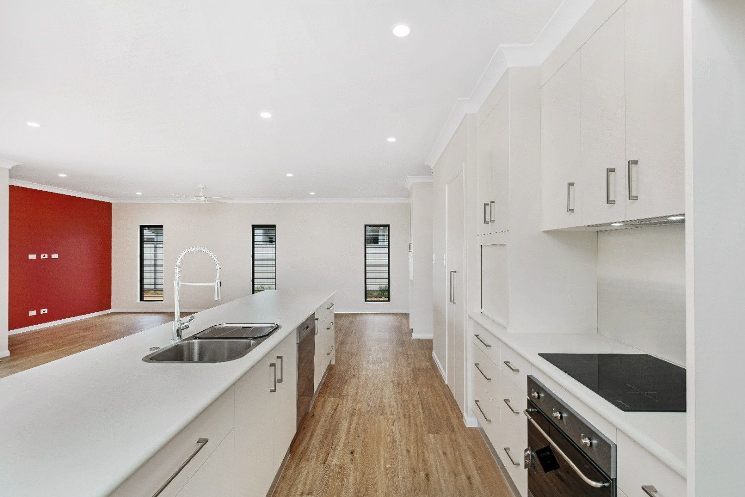 A Kitchen With White Cabinets and a Stove Top Oven — Ashlee Jones Homes in Gordonvale, QLD