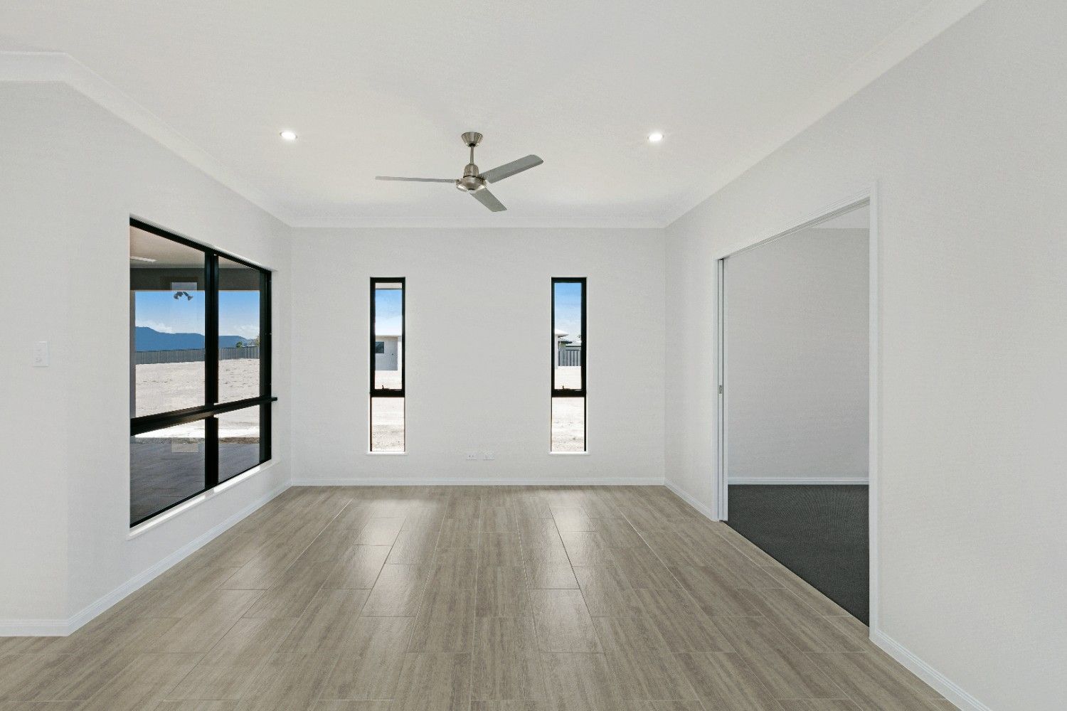 An Empty Room With a Ceiling Fan and Two Windows — Ashlee Jones Homes in Gordonvale, QLD