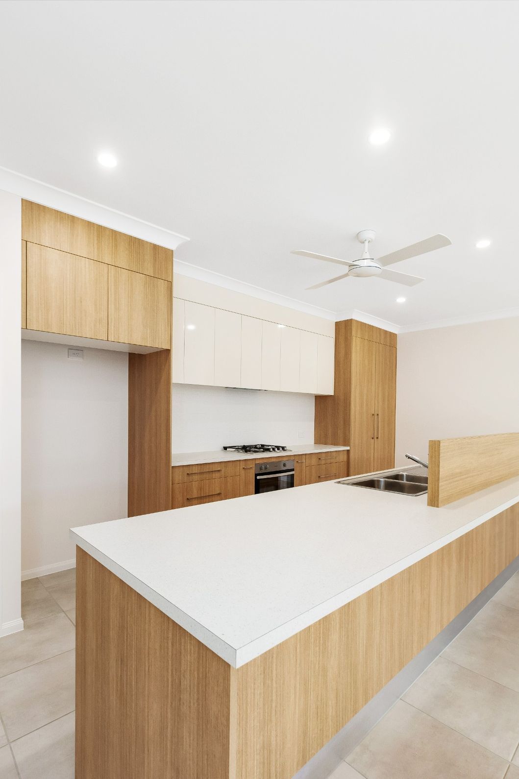 A Kitchen With Wooden Cabinets, White Counter Tops — Ashlee Jones Homes in Gordonvale, QLD