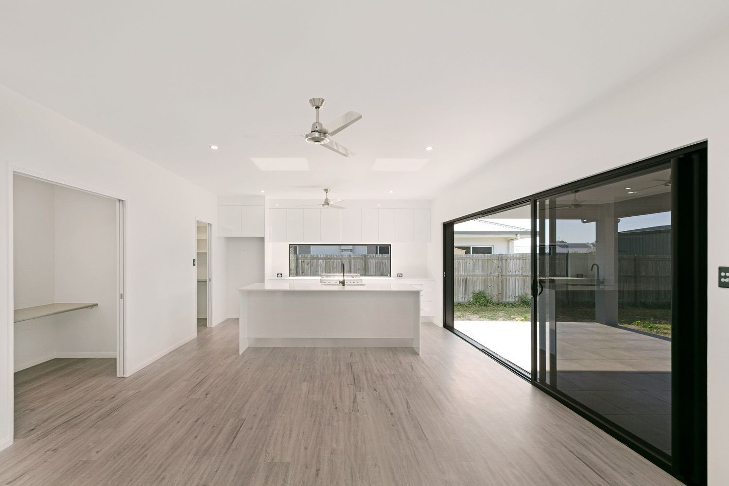 An Empty House With a Ceiling Fan and Sliding Glass Doors — Ashlee Jones Homes in Gordonvale, QLD