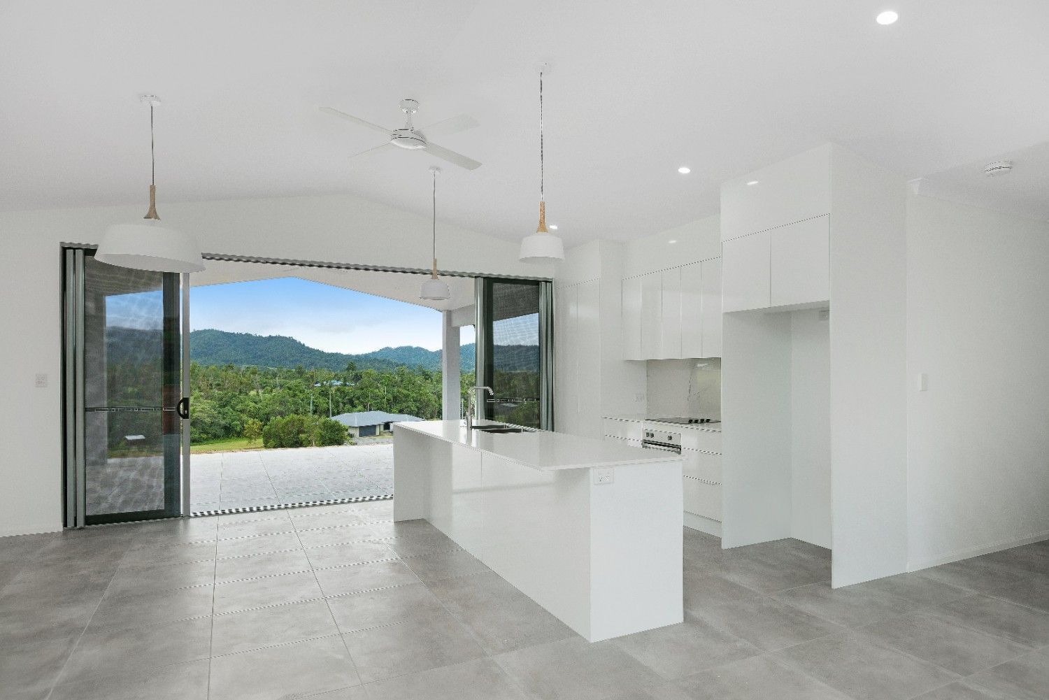 A Kitchen With White Cabinets and a Large Island With a View of the Mountains — Ashlee Jones Homes in Gordonvale, QLD