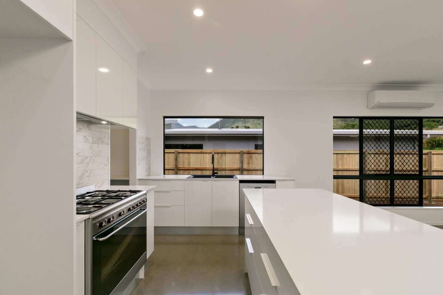 A Kitchen With White Cabinets and a Black Stove Top Oven — Ashlee Jones Homes in Gordonvale, QLD