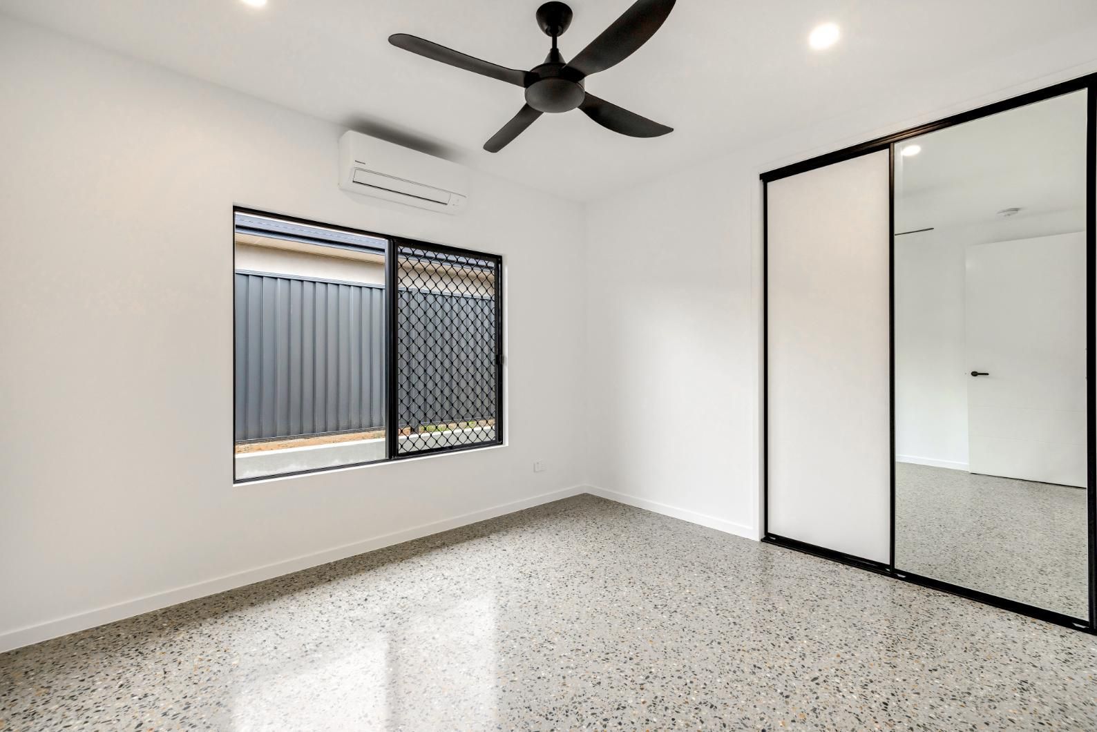 An Empty Bedroom with A Ceiling Fan and Mirrored Sliding Doors — Ashlee Jones Homes in Gordonvale, QLD