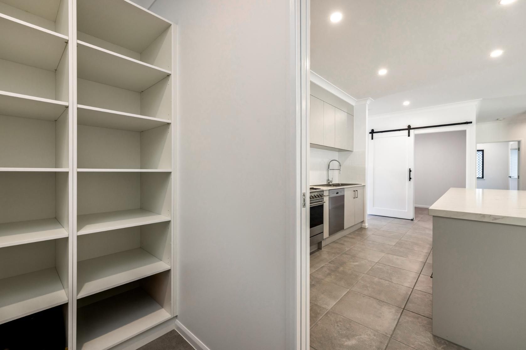 A Kitchen With a Sliding Barn Door Leading to a Pantry — Ashlee Jones Homes in Gordonvale, QLD