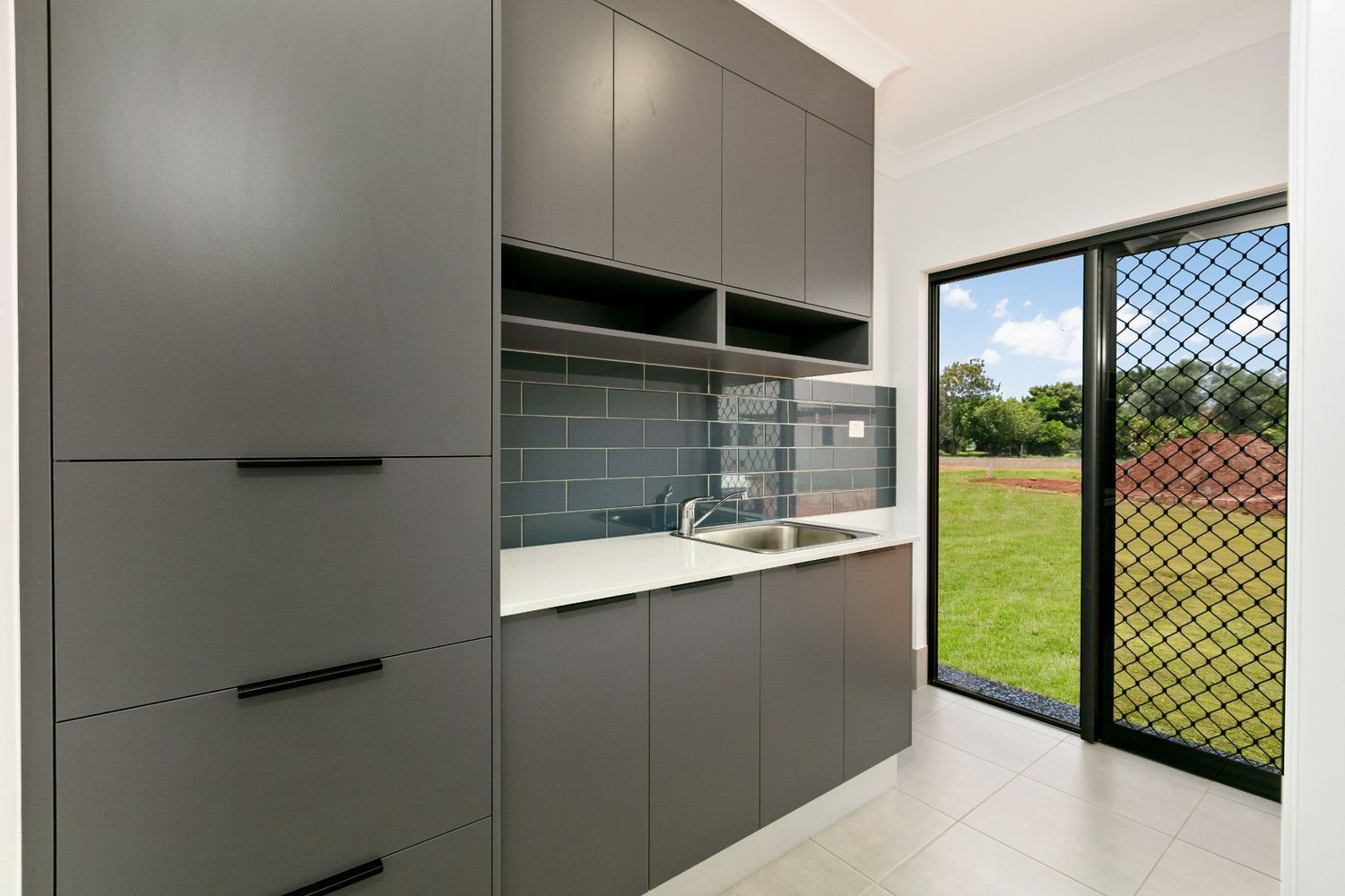 A Kitchen With a Sink, Cabinets and a Sliding Glass Door — Ashlee Jones Homes in Gordonvale, QLD