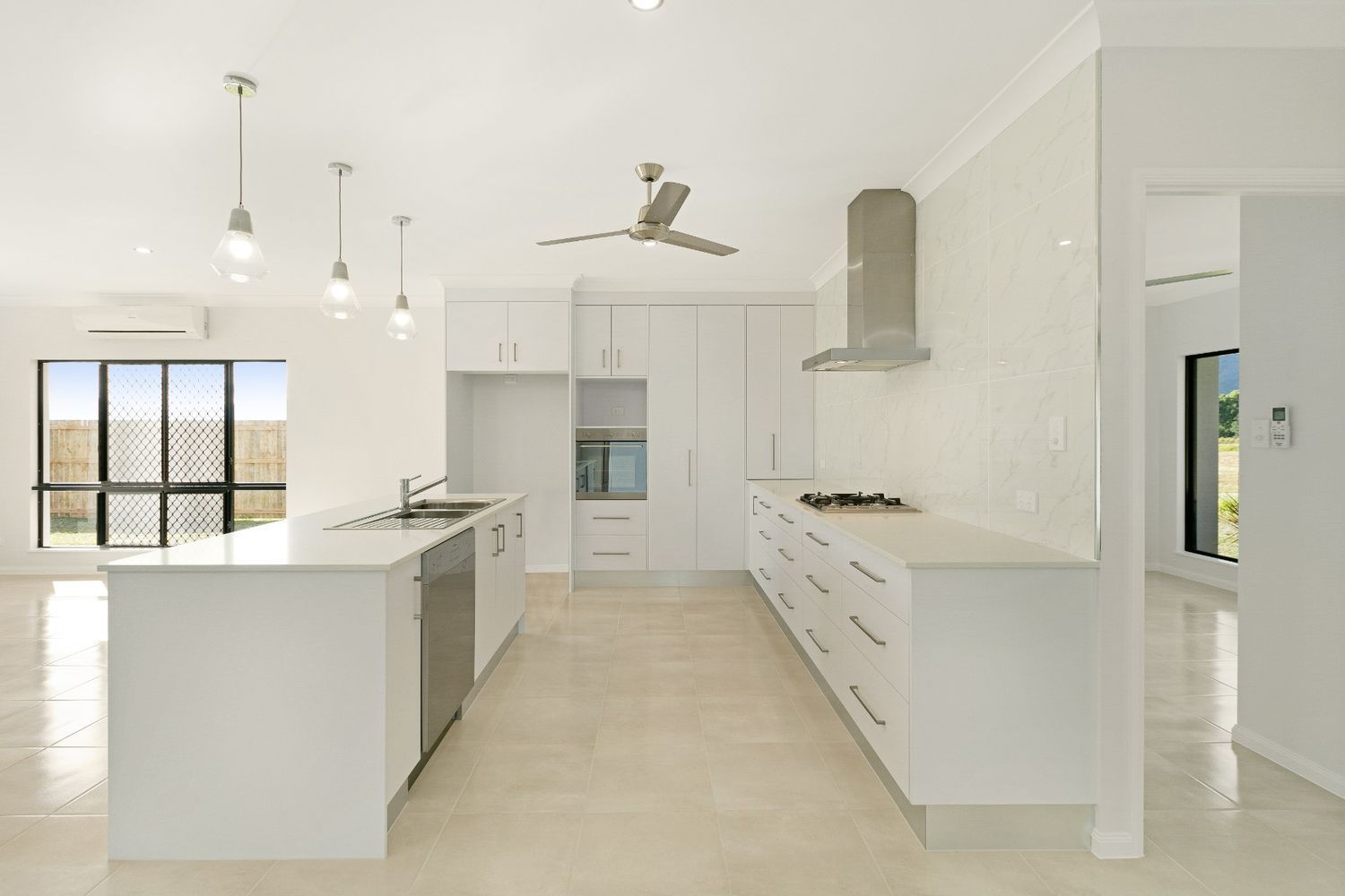 An Empty Kitchen With White Cabinets and a Ceiling Fan — Ashlee Jones Homes in Gordonvale, QLD