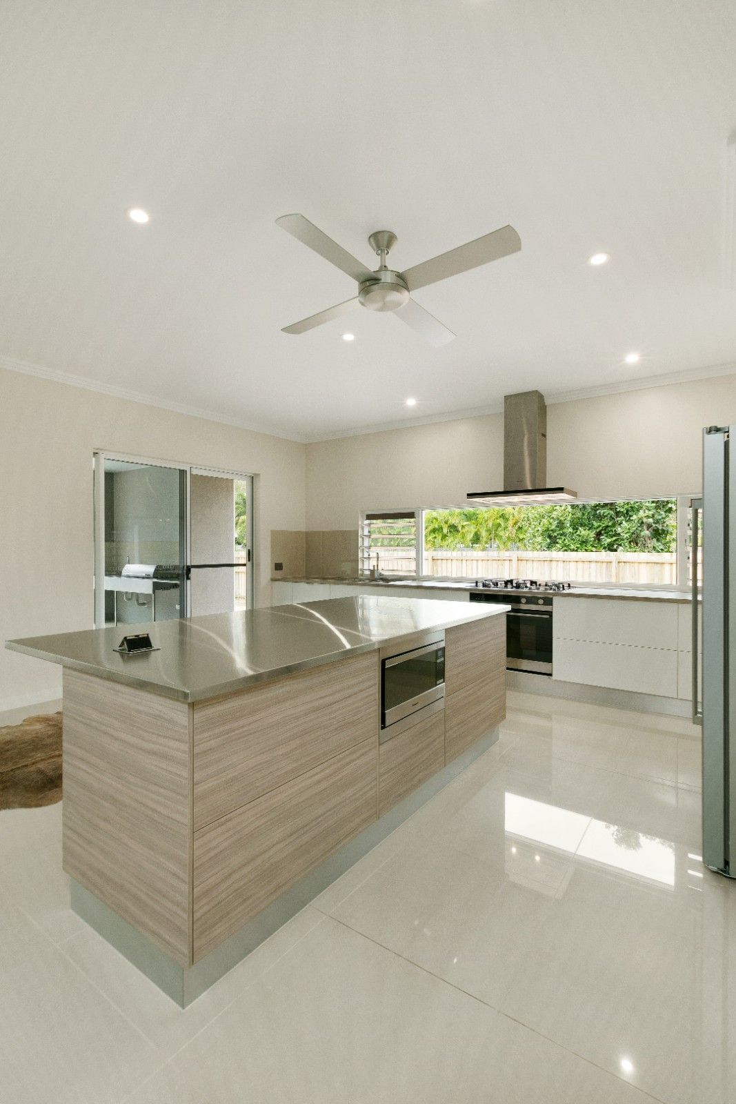A Walk in Closet With Lots of Shelves and a Sliding Glass Door Leading to an Empty Room — Ashlee Jones Homes in Gordonvale, QLD
