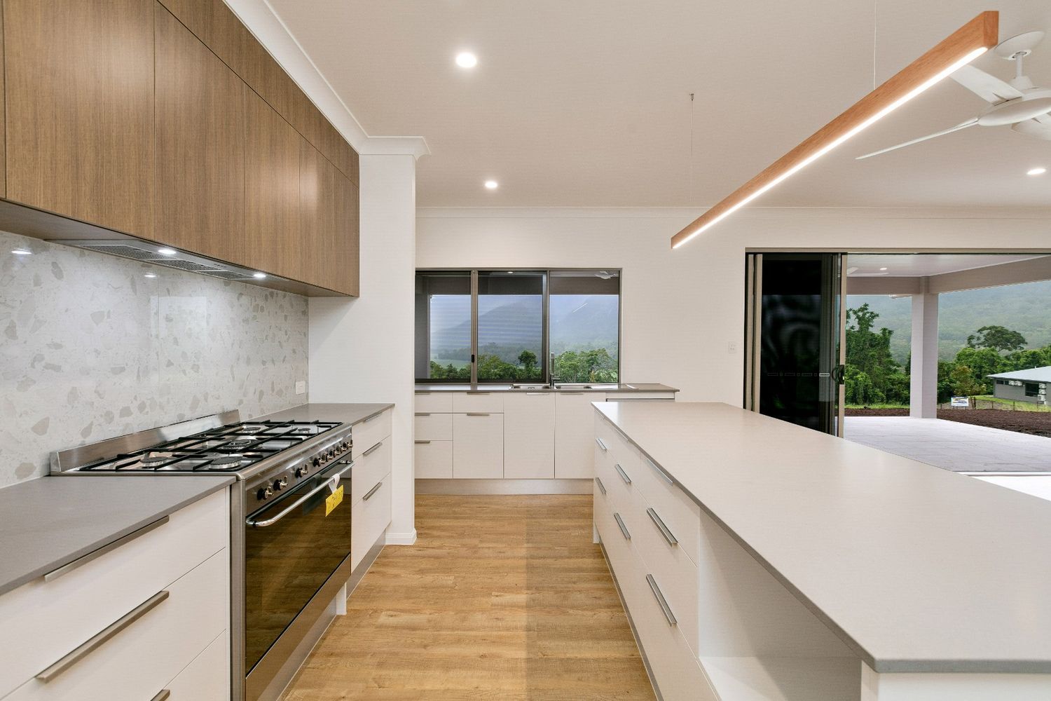 A Kitchen With a Large Island and Stove Top Oven — Ashlee Jones Homes in Gordonvale, QLD