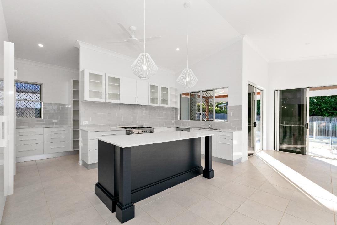 A Kitchen With White Cabinets and a Black Island in the Middle — Ashlee Jones Homes in Gordonvale, QLD