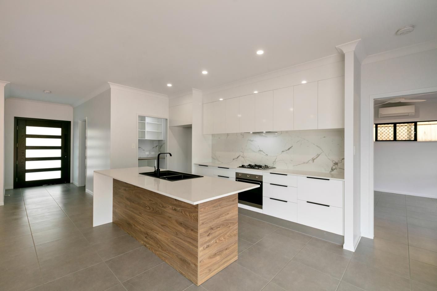 A Kitchen With White Cabinets and a Large Island in the Middle — Ashlee Jones Homes in Gordonvale, QLD
