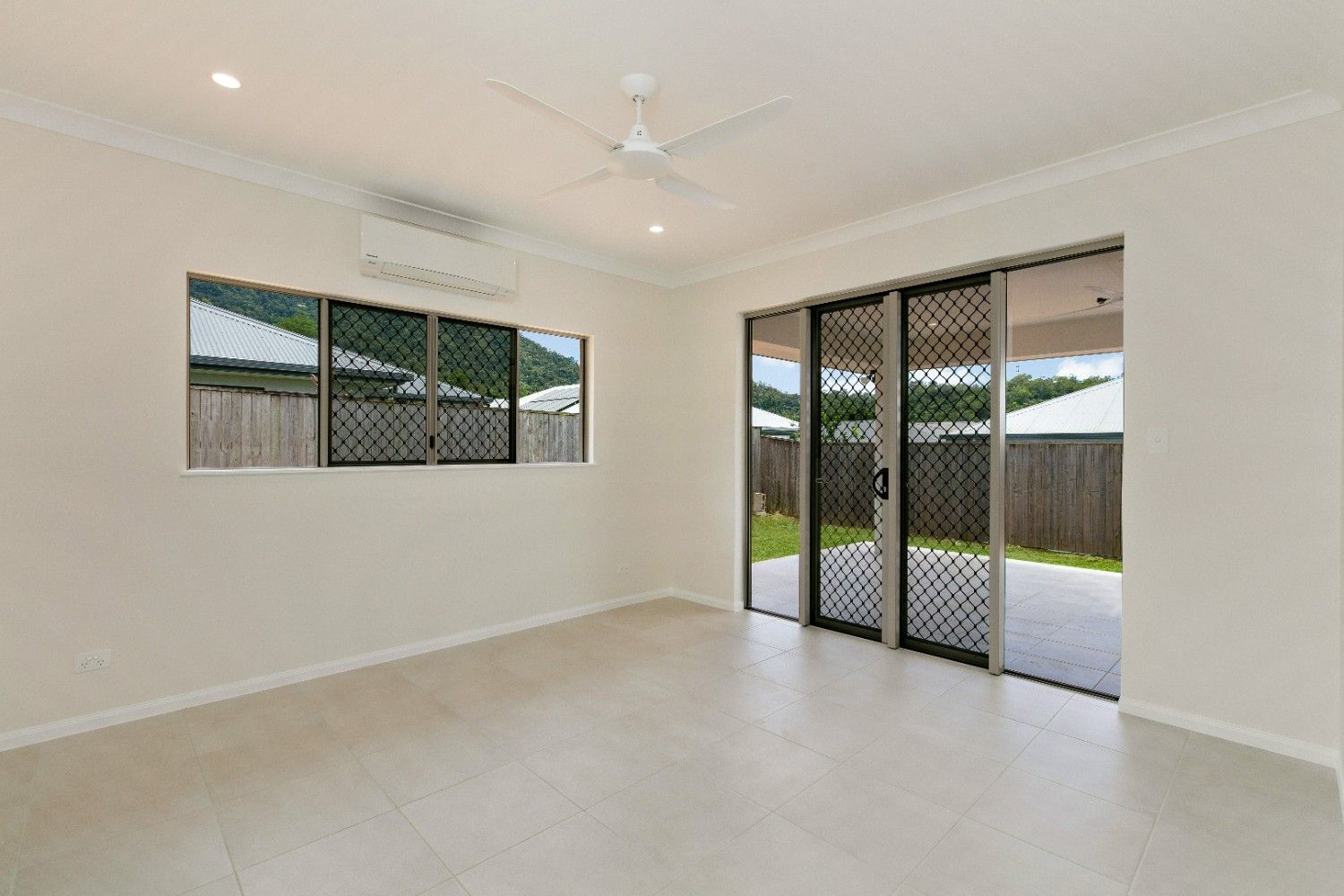 An Empty Living Room With Sliding Glass Doors and a Ceiling Fan — Ashlee Jones Homes in Gordonvale, QLD