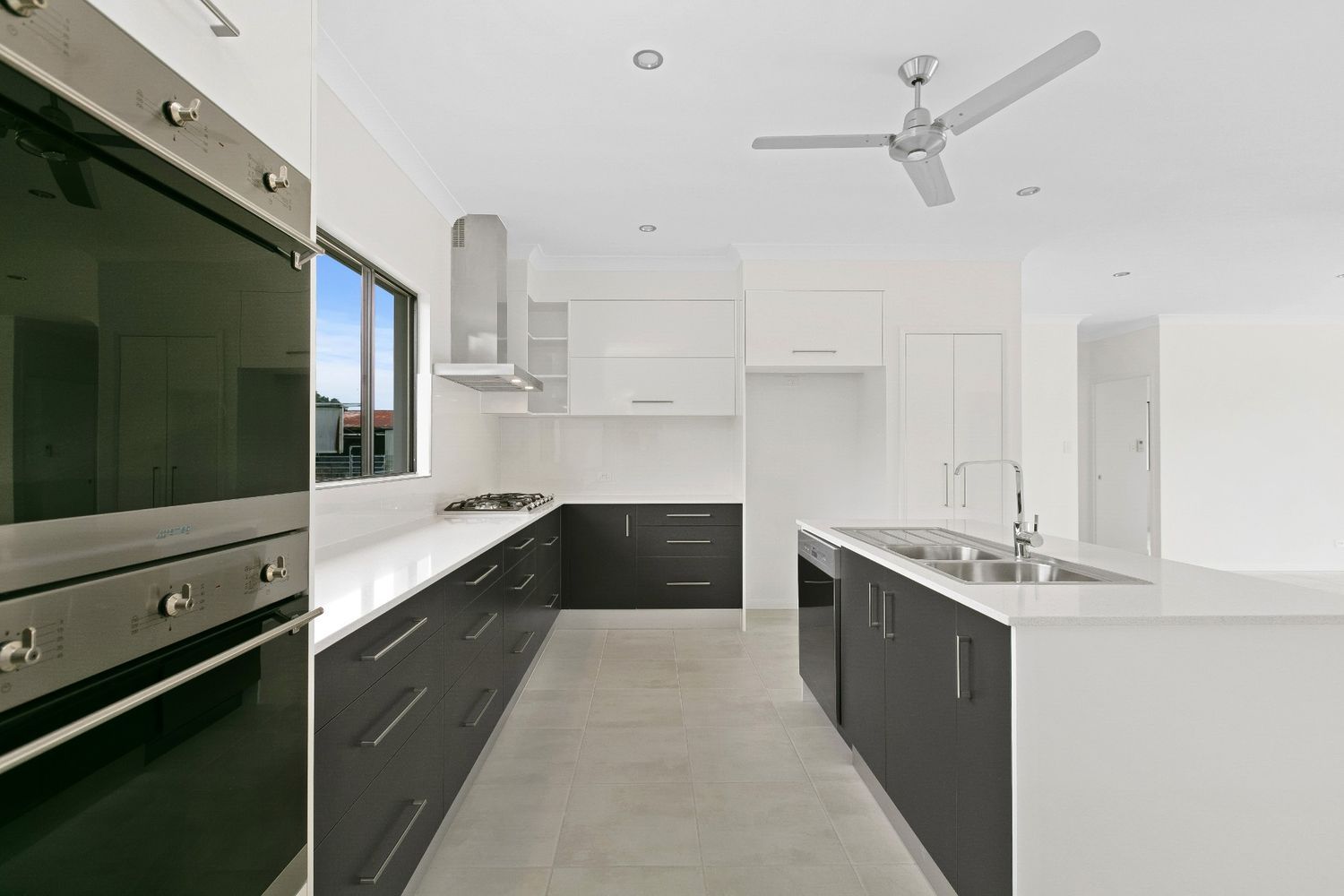 A Kitchen With Black Cabinets and a Ceiling Fan — Ashlee Jones Homes in Gordonvale, QLD