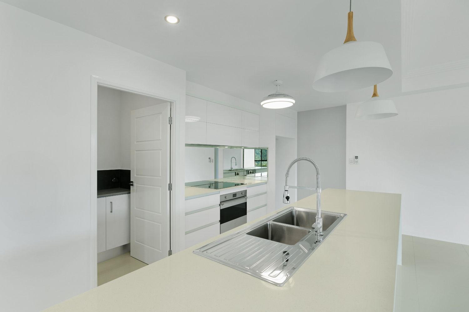 An Empty Kitchen With White Cabinets and a Sink — Ashlee Jones Homes in Gordonvale, QLD