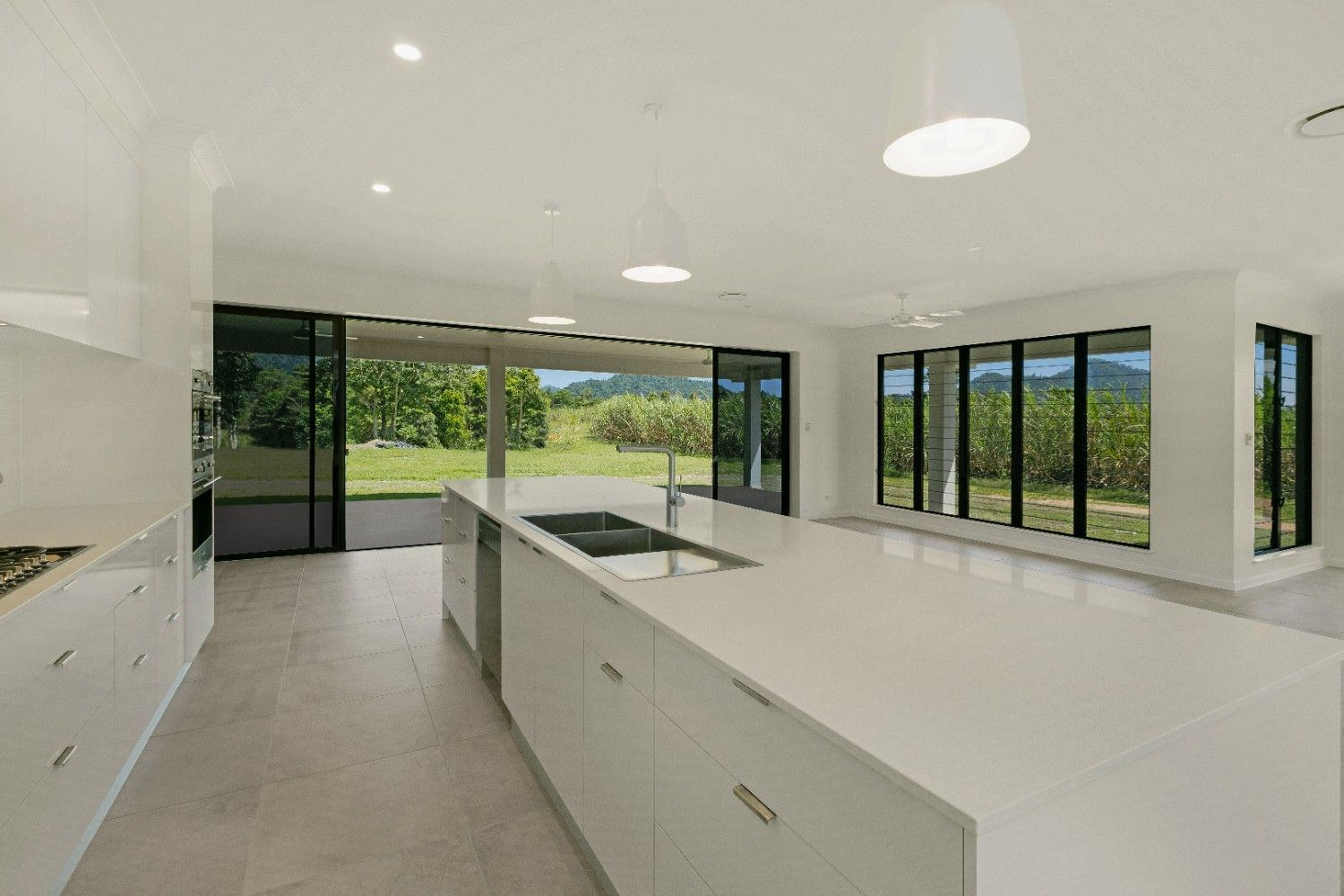 A Kitchen in a House With a Large Island and Lots of Windows — Ashlee Jones Homes in Gordonvale, QLD