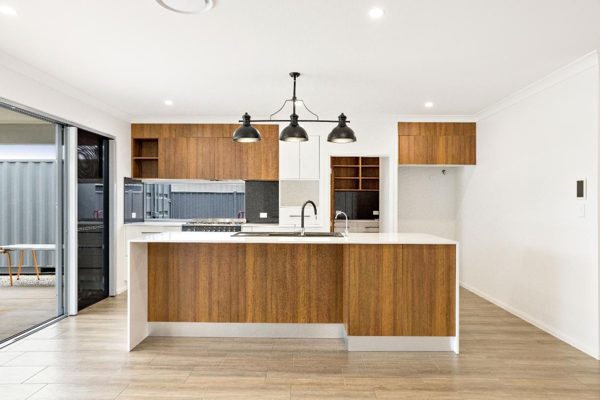 A Kitchen With Wooden Cabinets and a Large Island in the Middle of the Room — Ashlee Jones Homes in Gordonvale, QLD