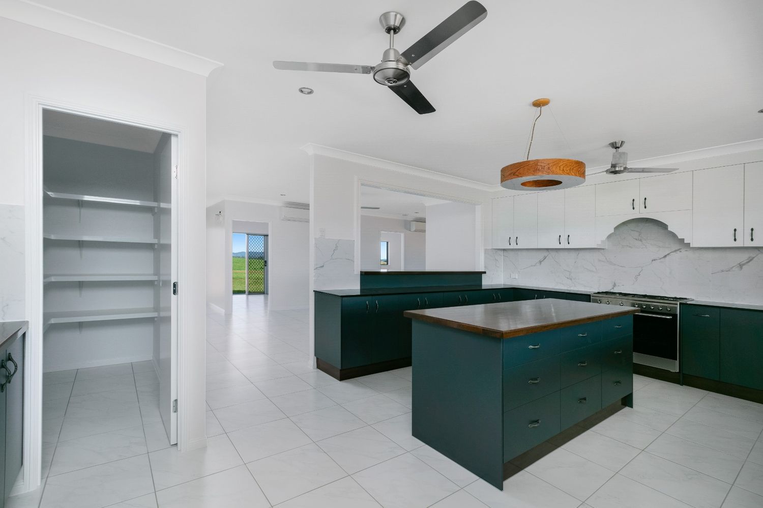 A Kitchen With a Large Island and a Ceiling Fan — Ashlee Jones Homes in Gordonvale, QLD