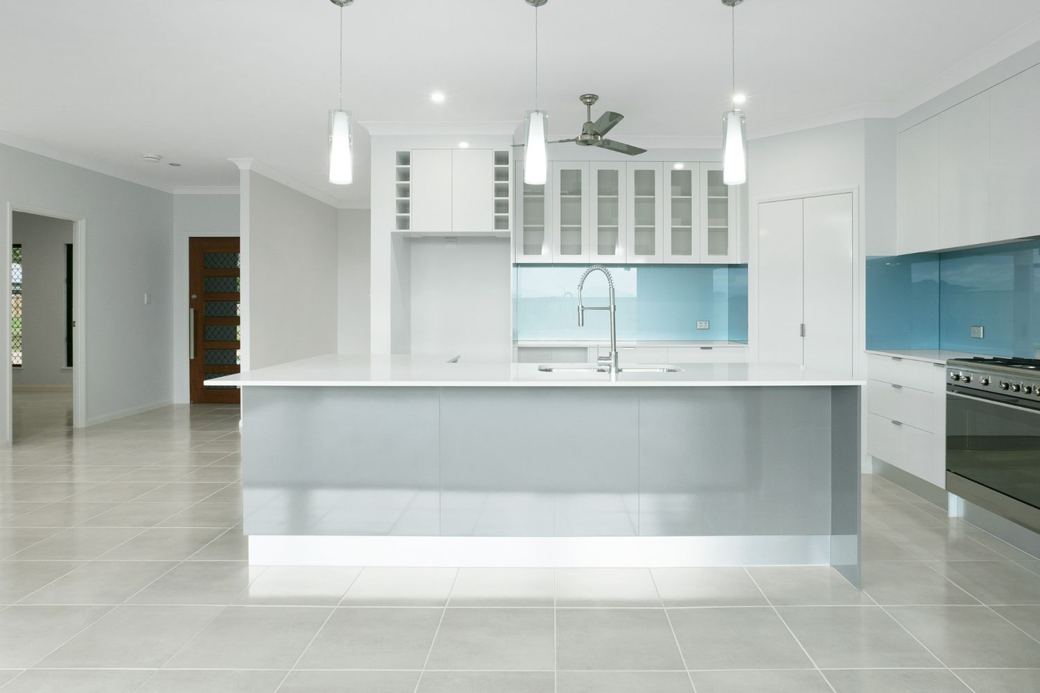 A Kitchen With a Large Island and a Ceiling Fan — Ashlee Jones Homes in Gordonvale, QLD