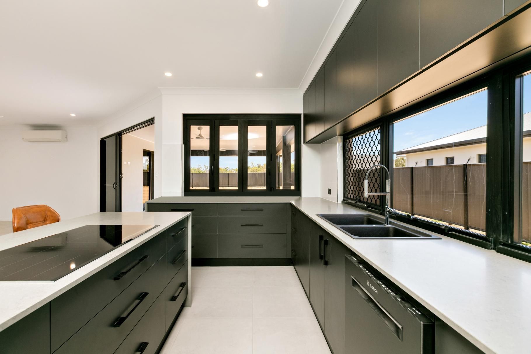 A Kitchen With Black Cabinets and White Counter Tops — Ashlee Jones Homes in Gordonvale, QLD