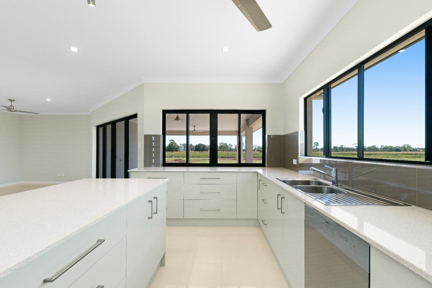 A Kitchen With White Cabinets, Stainless Steel Appliances, and a Large Island — Ashlee Jones Homes in Gordonvale, QLD