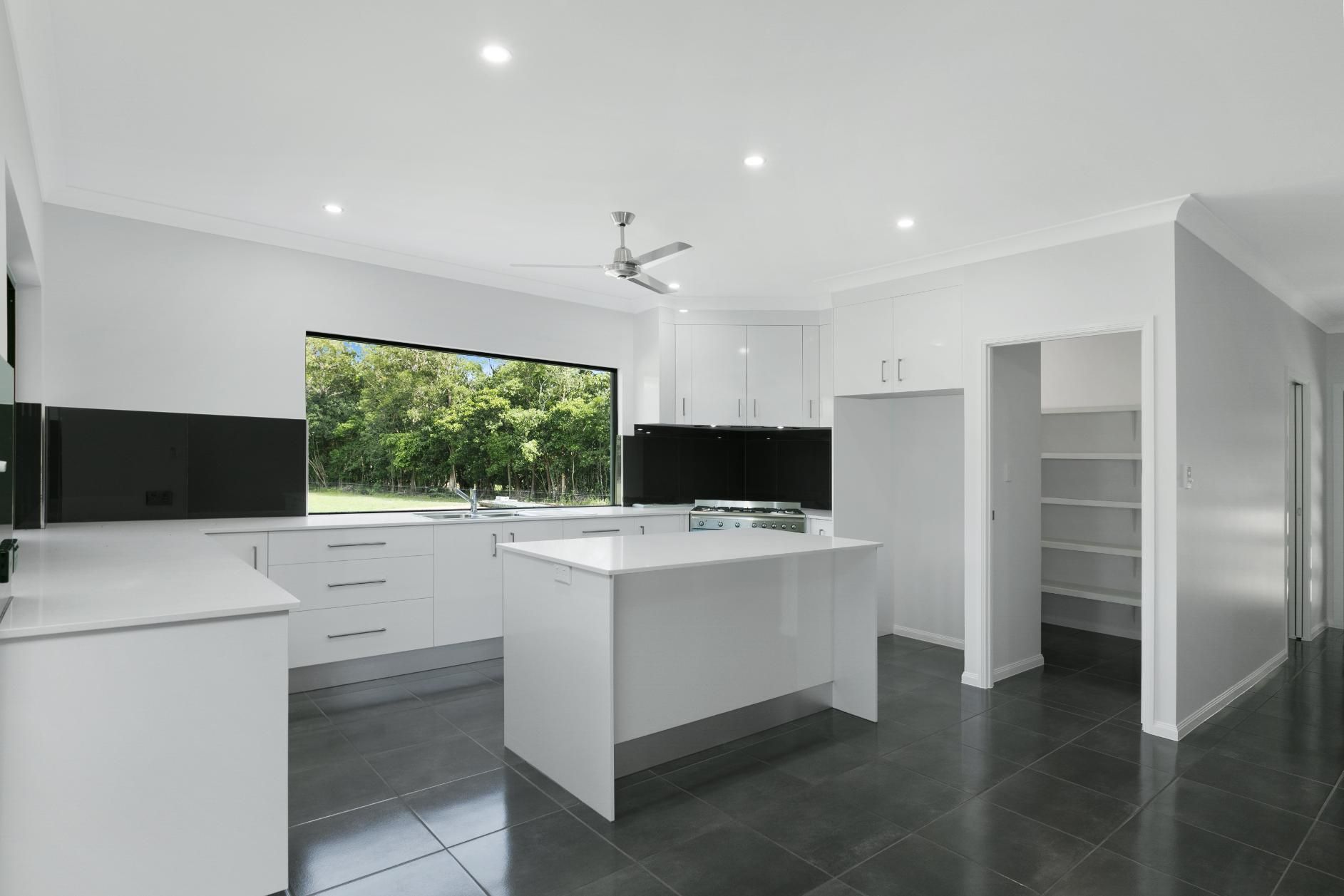 A Kitchen With White Cabinets and a Large Island in the Middle — Ashlee Jones Homes in Gordonvale, QLD