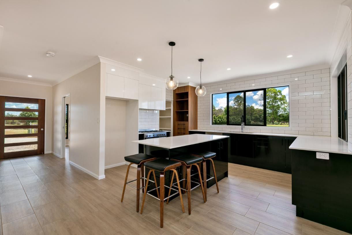 A Kitchen With a Large Island and Stools in It — Ashlee Jones Homes in Gordonvale, QLD