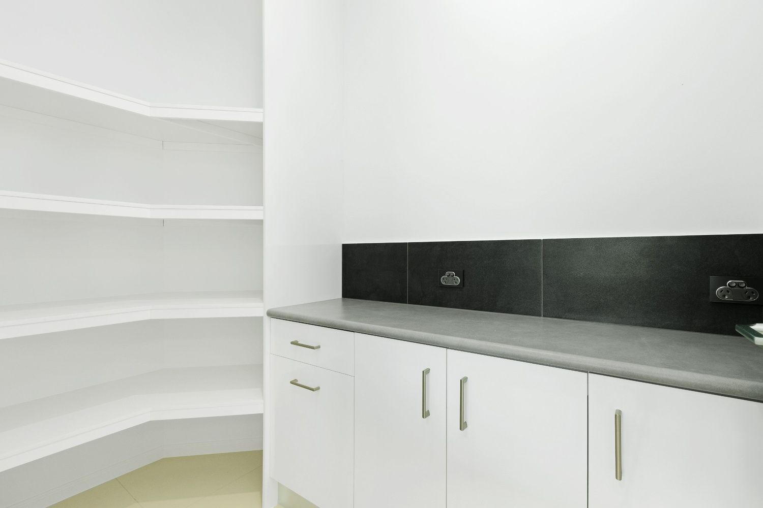 A Kitchen With White Cabinets and Black Counter Tops — Ashlee Jones Homes in Gordonvale, QLD