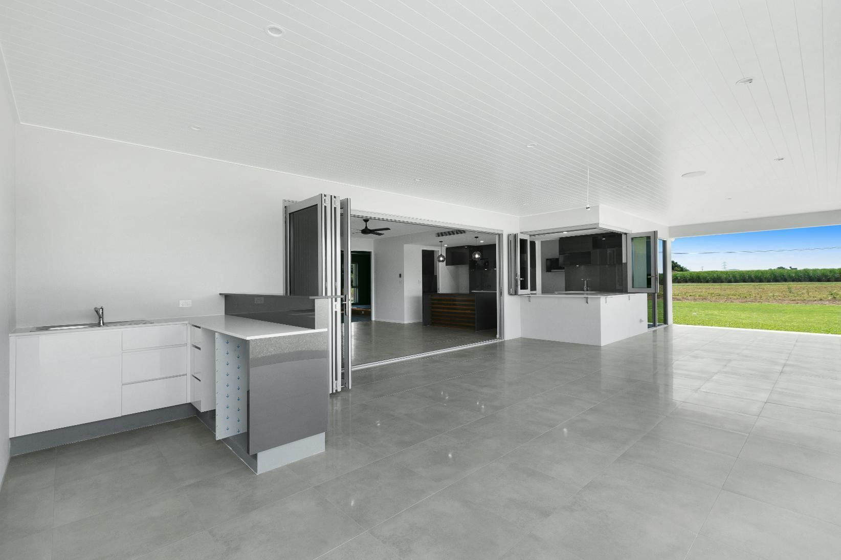 A Large Empty Room With a Kitchen and a Patio — Ashlee Jones Homes in Gordonvale, QLD