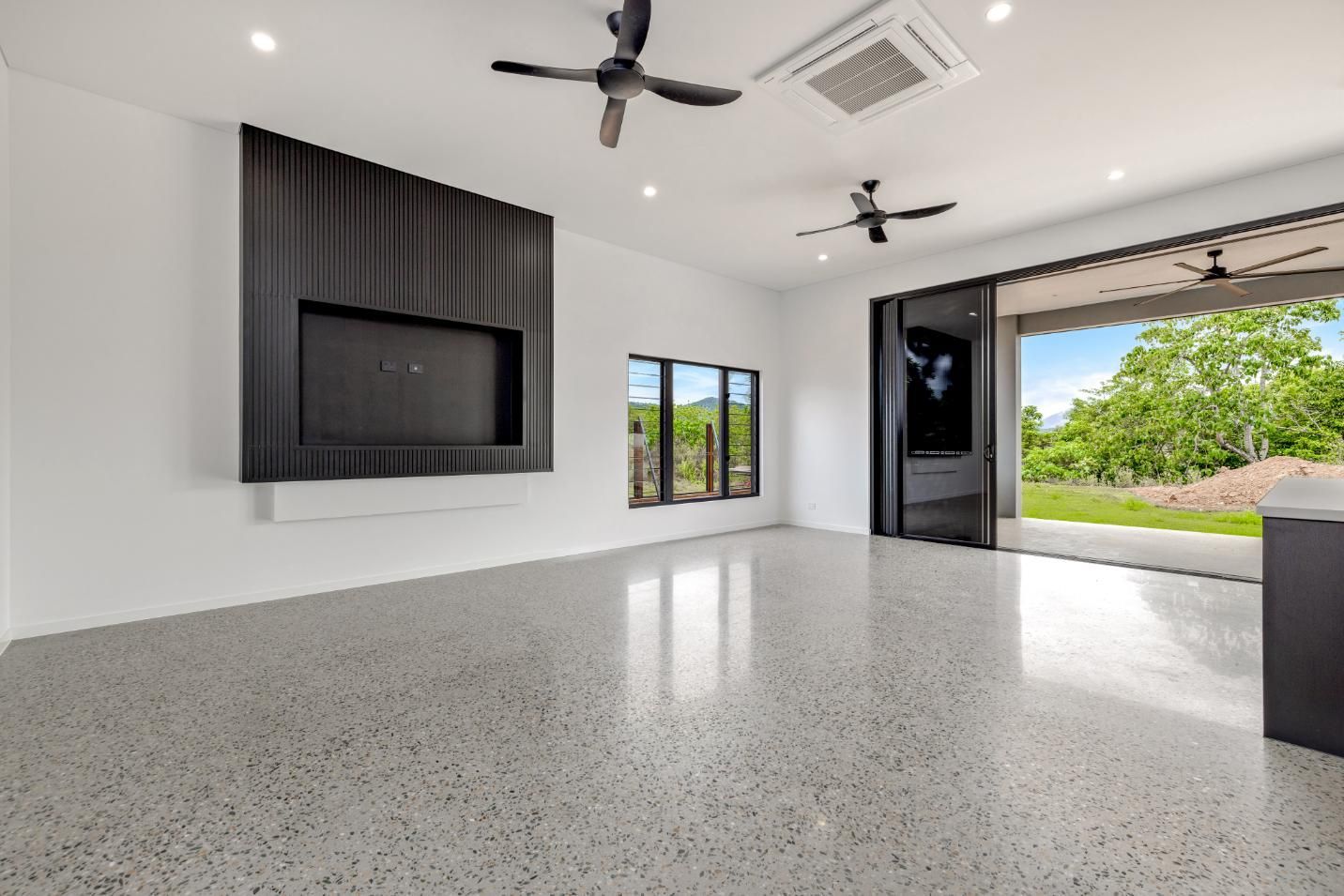 An Empty Living Room with A Ceiling Fan and A Flat Screen TV — Ashlee Jones Homes in Gordonvale, QLD