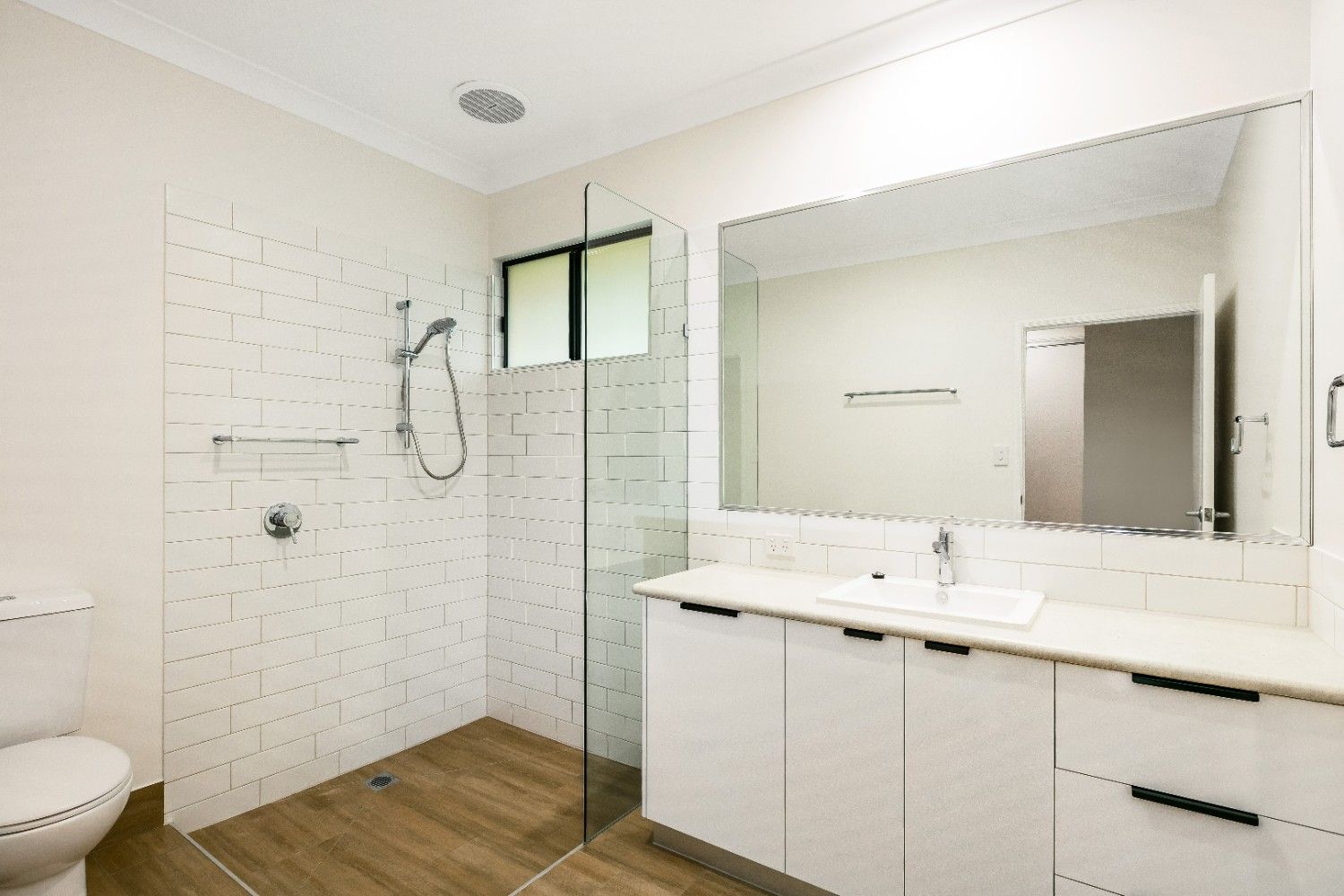 A Bathroom With a Toilet, Sink, Mirror and Walk in Shower — Ashlee Jones Homes in Gordonvale, QLD