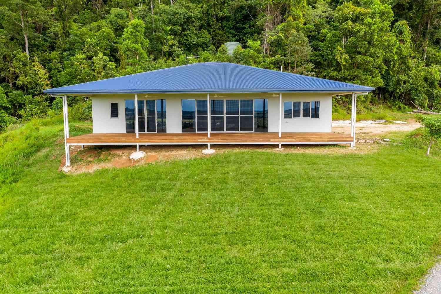 An Aerial View of a House With a Blue Roof and a Large Lawn in Front of It — Ashlee Jones Homes in Gordonvale, QLD