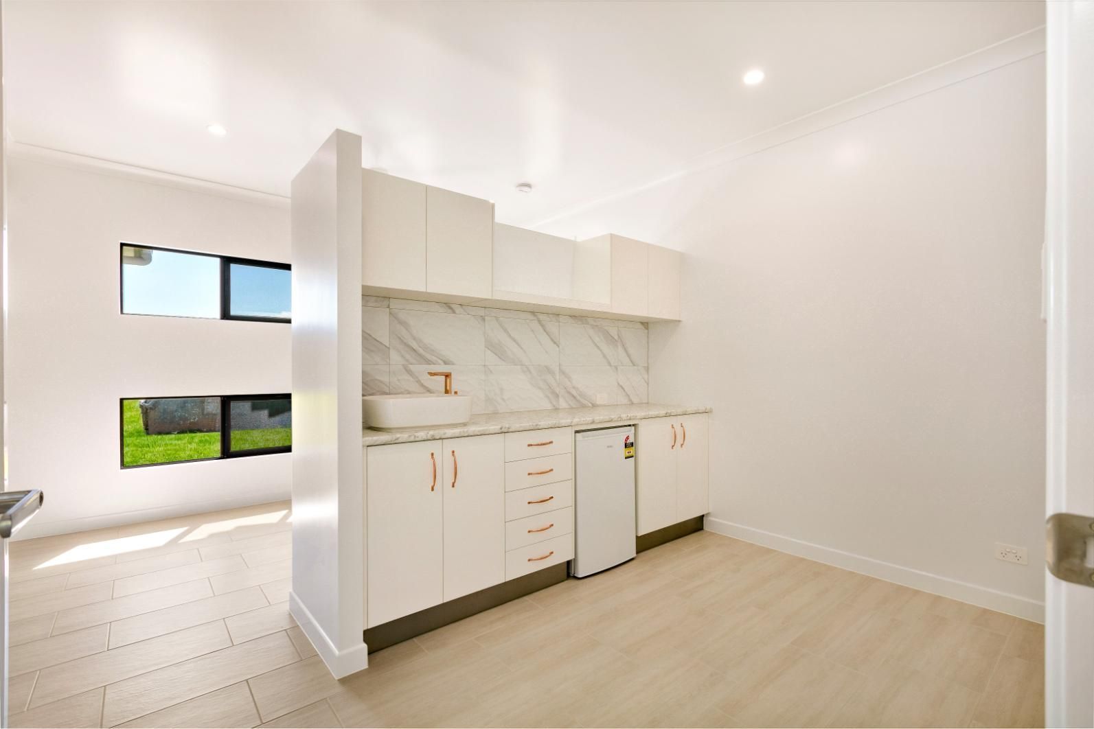 An Empty Kitchen With White Cabinets and Marble Counter Tops — Ashlee Jones Homes in Gordonvale, QLD